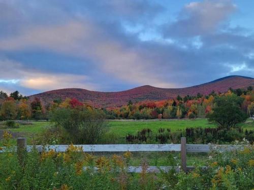 a field with a fence and mountains in the background at Mountain house w/ stunning views & gourmet kitchen in Maplecrest