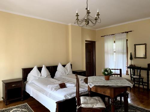 ein Schlafzimmer mit einem Bett, einem Tisch und einem Kronleuchter in der Unterkunft Bokréta in Zetea
