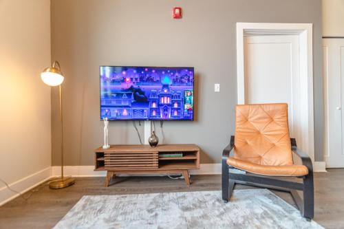 a living room with a tv and a chair at Modern 2BR Loft with Amazing City Skyline View and Optional Parking for 8 Guests Near McCormick Place and Soldier Field in Chicago