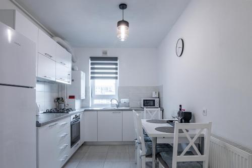 una cucina con elettrodomestici bianchi, tavolo e sedie di Apartment with free parking near Coresi Mall by MM Apartments a Braşov