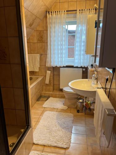 a bathroom with a sink and a toilet and a tub at Zimmer m. Doppelbett, Zustellbett f. 3. Pers. mgl. in Reppenstedt