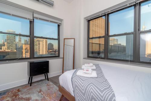 een slaapkamer met een bed en ramen met uitzicht op de skyline van de stad bij McCormick place luxury Penthouse Duplex with personal rooftop with optional parking for 8 guests in Chicago