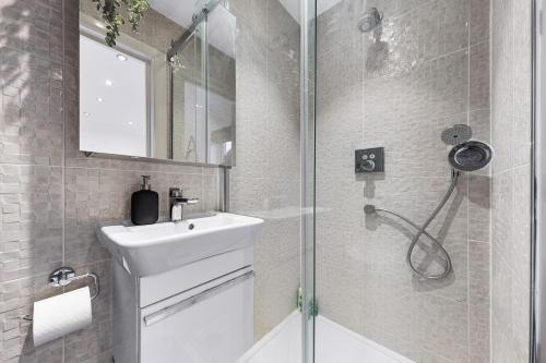 a bathroom with a white sink and a shower at Elegant Serviced Apartment Studio - Central London in London