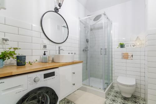 a white bathroom with a sink and a shower at Apartament Turkus z basenem in Sztutowo