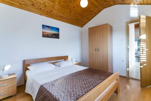 een slaapkamer met een groot bed en een houten plafond bij Holiday Home Nina Plitvine in Vela Luka