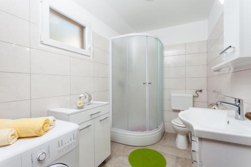 een witte badkamer met een douche en een wastafel bij Holiday Home Nina Plitvine in Vela Luka
