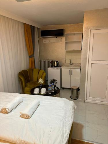 a bedroom with a bed and a chair and a kitchen at RUDOLF SUİT APART in Ankara