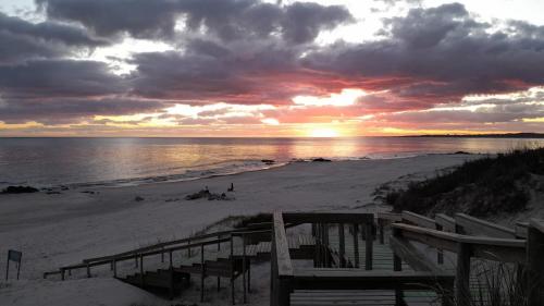 una puesta de sol en una playa con bancos en la arena en Casa Familiar 6 per con Vista Se RESERVA Con SEÑA UTE APARTE, en San Luis