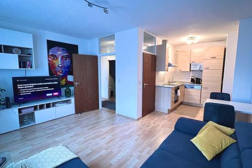 ein Wohnzimmer mit einem blauen Sofa und einer Küche in der Unterkunft Apartment 14 im Herzen von Linz in Linz