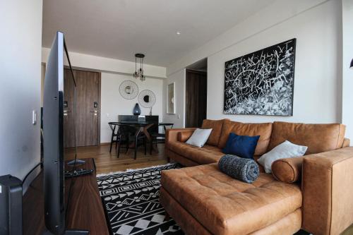 a living room with a brown couch and a tv at Lujoso y cómodo departamento en la mejor zona de Condesa in Mexico City