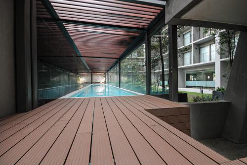 a swimming pool in a building with a wooden deck at Lujoso y cómodo departamento en la mejor zona de Condesa in Mexico City