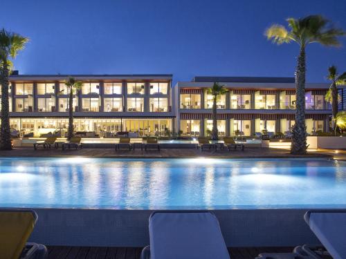 a hotel with a large swimming pool at night at Pestana Alvor South Beach Premium Suite Hotel in Alvor