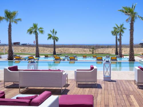 a large swimming pool with chairs and palm trees at Pestana Alvor South Beach Premium Suite Hotel in Alvor
