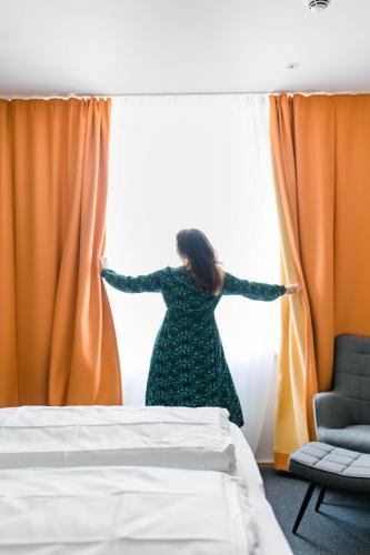 a woman in a dress is looking out of a window at Stadthotel Freilassing in Freilassing