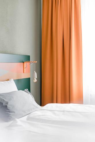 a bedroom with a bed with an orange curtain at Stadthotel Freilassing in Freilassing