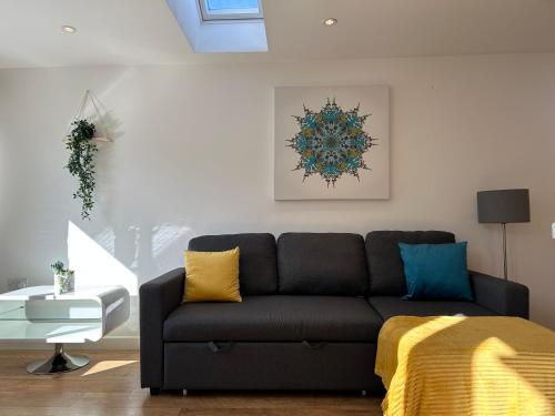a living room with a black couch with yellow pillows at Stylish 1 Bedroom Flat with Parking in Oxford in Oxford