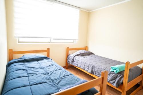 2 camas en un dormitorio con ventana en Disfruta de un tranquilo departamento en el centro a pasos del Hipodromo en Santiago