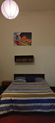 a bedroom with a bed with a blue and white striped blanket at Azul Profundo Hostal Cultural in Valparaíso
