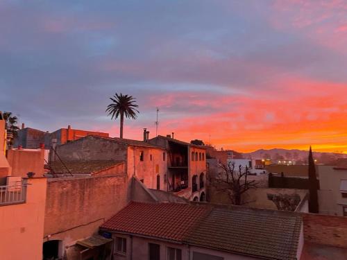 a city skyline with a palm tree and buildings at Costa Brava acollidor apartament amb gran terrassa per a 3 persones in Castelló d'Empúries