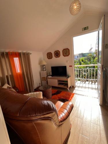sala de estar con sofá de cuero y balcón en Tropical House, en Ribeira Brava