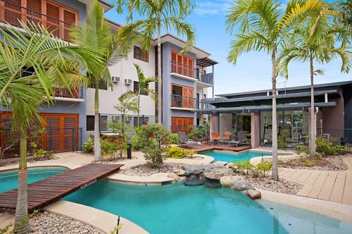 a building with two swimming pools and palm trees at Southern Cross Atrium Apartments in Cairns