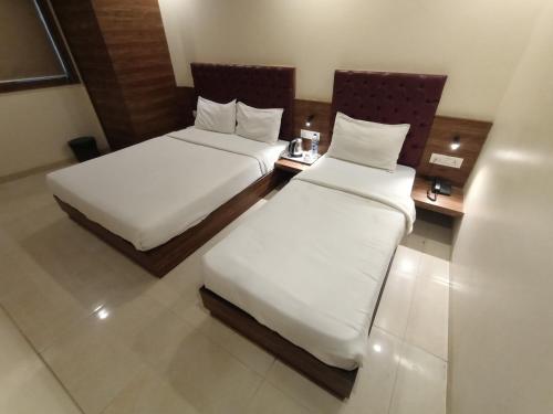 two beds in a hotel room with white sheets at Hotel New Peninsula Suite - Near Masjid Bandar and CST Station - South Mumbai in Mumbai