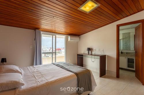 a bedroom with a bed and a large window at Apto luxuoso a 450m da praia em Floripa ADI0302 in Florianópolis