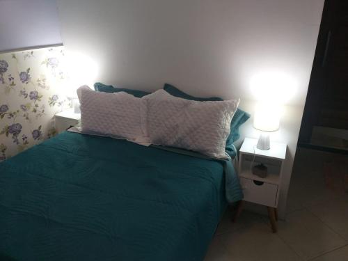 ein Schlafzimmer mit einem grünen Bett mit zwei Kissen darauf in der Unterkunft Suite Grande Rio in Duque de Caxias