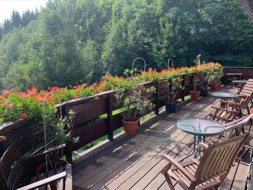 una terraza de madera con mesas, sillas y flores en Agropajda, en Sokolec