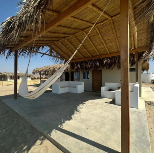 uma rede pendurada num telhado de palha numa praia em Vichayito, Órganos, Casa Serendipity em Vichayito