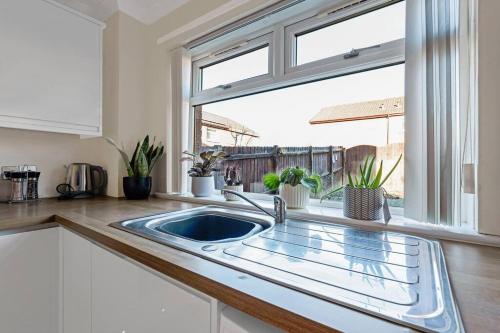 une cuisine avec un évier et une fenêtre dans l'établissement Stylish 2-Bed House Private Driveway, à Glasgow