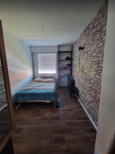 une chambre avec un lit et un mur de briques dans l'établissement Petit appart Colmar - ingersheim, à Ingersheim