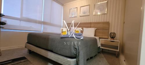 a bedroom with a bed with a gray comforter at MC Suite - Centro in Antofagasta