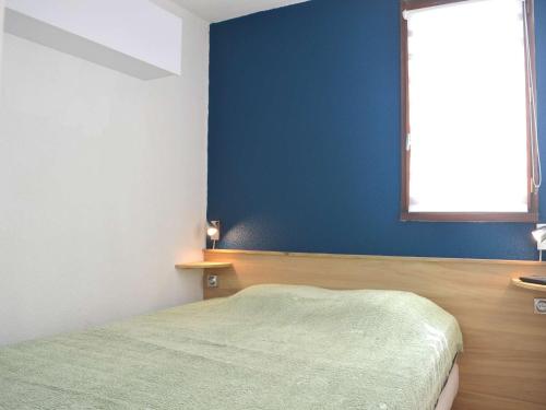 une chambre avec un lit et un mur bleu dans l'établissement Appartement T2 avec Piscine, 4 Couchages, Proche Plage - Narbonne Plage - FR-1-229B-97, à Narbonne