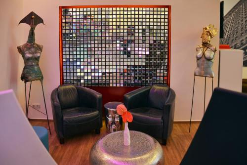 a room with two mannequins and two chairs and a table at Arthotel Munich in Munich