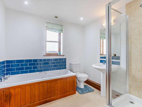 a bathroom with a tub and a toilet and a sink at 2 Bed in Bude 51764 in Pyworthy