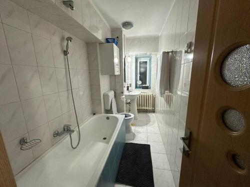 y baño con bañera, aseo y lavamanos. en Decebal apartment overlooking the boulevard, en Bucarest