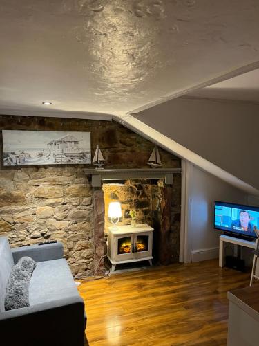 uma sala de estar com uma parede de pedra e uma televisão em Largs Top Floor Flat em Largs
