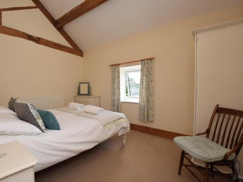 two beds in a room with a window and a chair at 2 Bed in Ashford in the Water PK502 in Great Longstone
