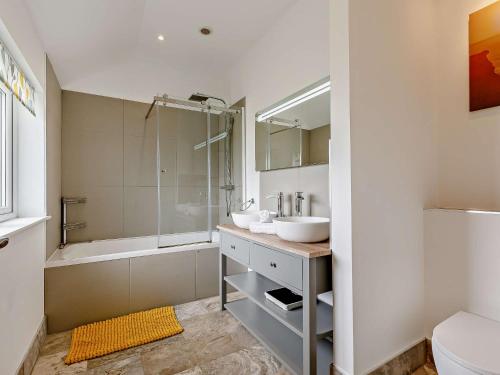 ein Badezimmer mit 2 Waschbecken, einer Dusche und einer Badewanne in der Unterkunft 4 Bed in Bude 50591 in Bude