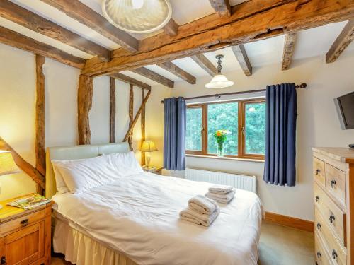 a bedroom with a bed with blue curtains and a window at 3 Bed in Bewdley THFIS in Highley