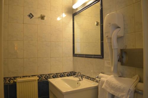 a bathroom with a sink and a toilet and a mirror at Hotel Le Beau Site in Saint-Pierre-de-Chartreuse