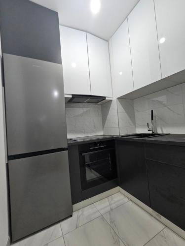 eine Küche mit weißen Schränken und einem Kühlschrank aus Edelstahl in der Unterkunft Apartman Urukalo in Rebrovac