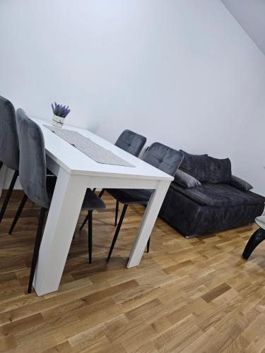 einen weißen Esstisch mit schwarzen Stühlen und einem Sofa in der Unterkunft Apartman Urukalo in Rebrovac