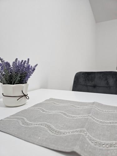 einen Tisch mit einem grauen Teppich und eine Vase mit lila Blumen in der Unterkunft Apartman Urukalo in Rebrovac