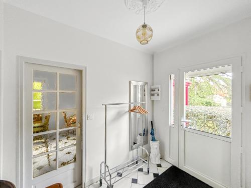un couloir blanc avec une porte vitrée et un dressing dans l'établissement Jardin Secret - Maison Proche de l'Hippodrome, à Orléans