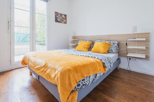 een slaapkamer met een bed met gele lakens en een raam bij Cocooning YourHostHelper in Serris