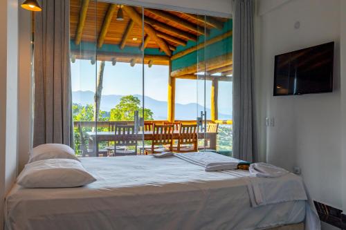 um quarto com uma cama e vista para uma varanda em Casa Bambolê em Ilhabela em Ilhabela