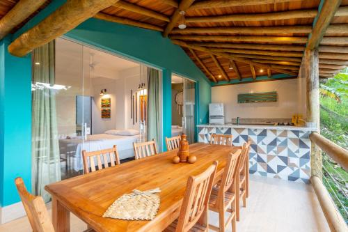 ein Esszimmer mit einem Holztisch und einer Küche in der Unterkunft Casa Bambolê em Ilhabela in Ilhabela