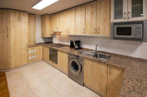 cocina con armarios de madera, fregadero y lavavajillas en Apartamento Baztan Berri, en Elizondo